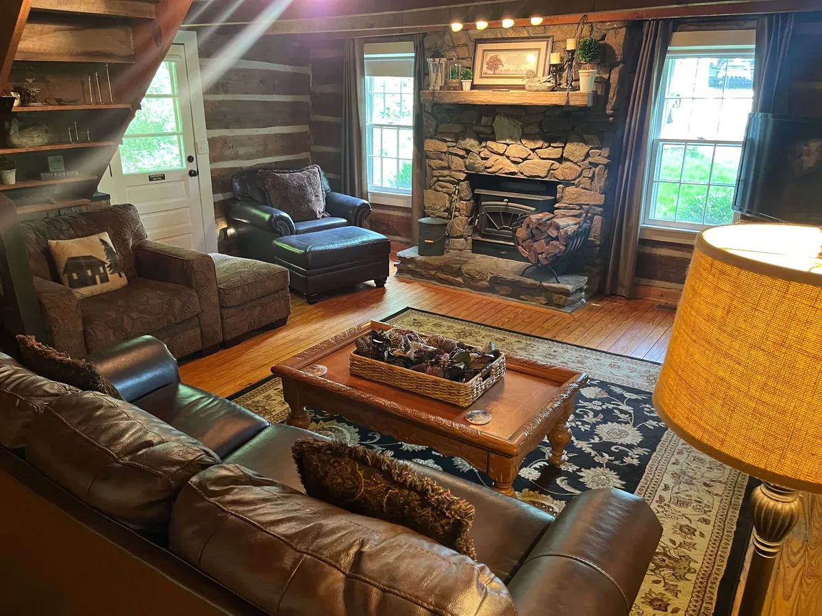 A welcoming interior scene with a stone fireplace, inviting and comfortable seating arranged for conversation or relaxation, and a sturdy wooden coffee table, all surrounded by rustic cabin decor.